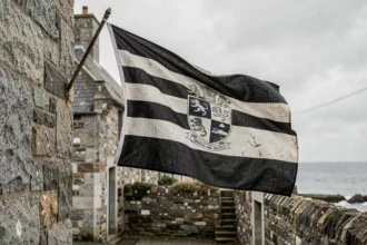 Drapeau breton Gwenn-ha-du accroché sur un mur en granit dans un village côtier de Bretagne